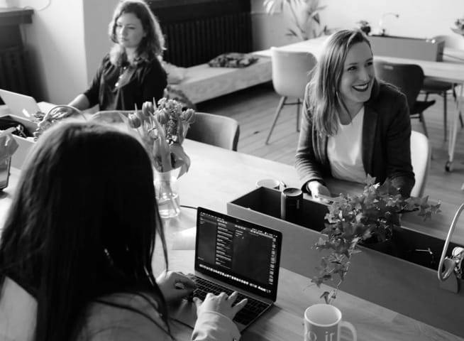 Women sitting in front of computers in a cozy workspace.